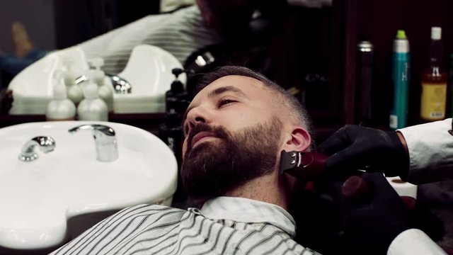 A man client visiting haidresser in barber shop, beard trimming.