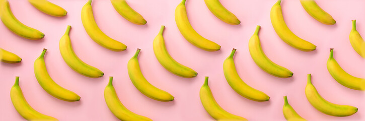 Geometric colorful fruit pattern. Bananas over pink background. Banner. Top view. Pop art design, creative summer concept. Minimal flat lay style.