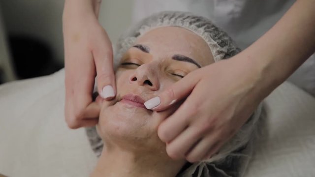 Woman doing facial massage at the spa salon.