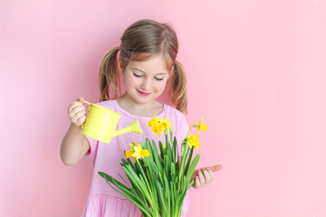 Beautiful girl holding a flowers and watering can on a pink background.