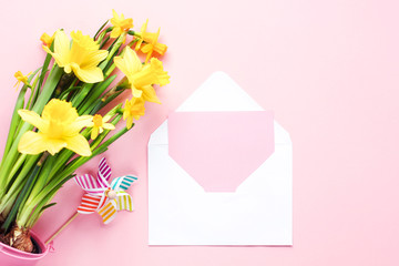 Yellow flowers and envelope on pink background. Mockup with card. Flat lay, top view