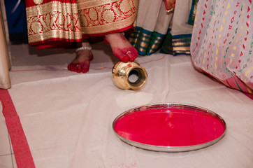 Indian wedding rituals, Gruha Pravesh / Gruhapravesh / Griha Pravesh, closeup picture of right feet of a Newly married Indian Hindu bride dipping her fit in a plate filled with liquid kumkum then step