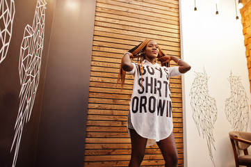 Beautiful african woman in stylish casual clothes posing against angel wings wall. She moving her...