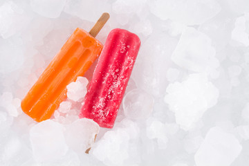 Orange and strawberry popsicles on ice cubes. Top view. Copyspace