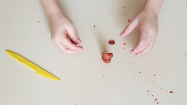 The child molds a figure from plasticine. Close-up of children's hands. Flatley