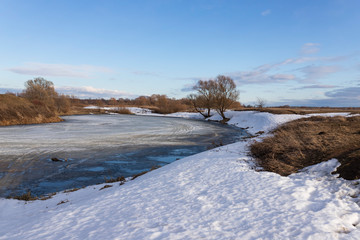 Spring landscape. Coast of the frozen pond