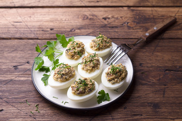 Stuffed eggs with mushrooms, cream cheese and parsley on a wooden table