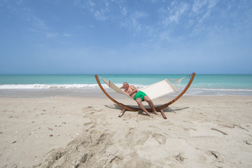 Fototapeta na wymiar man lying on a hammock resting on the beach
