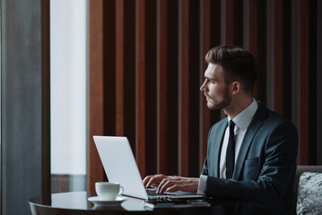 Young businessman working on a plan of Internet project on the laptop. Man discusses business matters by phone. Working computer for internet research. Digital marketing. Development