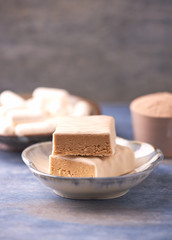 Protein bar in two pieces, creatine capsules and scoop. Bodybuilding food supplements on rustic wooden background. Copy space.