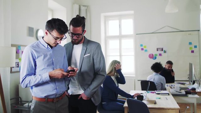 Group of young businesspeople with smartphone working together in a modern office.