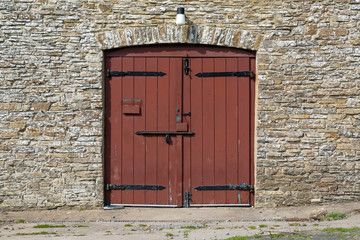 An old coach house doorway entrance with a modern door fitted with three security bolts