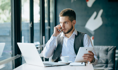 Young handsome businessman conducting negotiations with investors. Electronic business. Alternative...