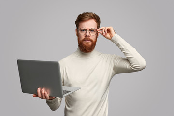 Serious programmer with laptop looking at camera