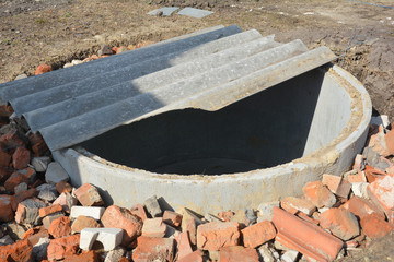 Installing concrete septic tank. Sewer tank hole installation outdoors