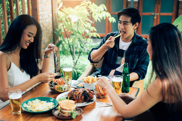 Asian people cheering beer at restaurant happy hour and laughing.