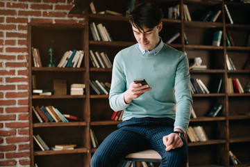 Young handsome student typing on his notebook his diploma. Student discussing on the phone universities's timetable. Education online. Work on freelance. Software development.