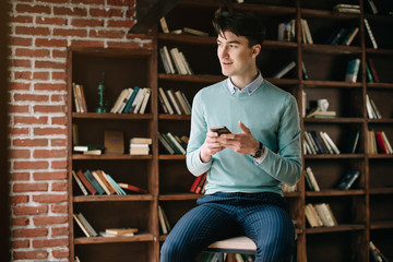 Young handsome student typing on his notebook his diploma. Student discussing on the phone universities's timetable. Education online. Work on freelance. Software development.