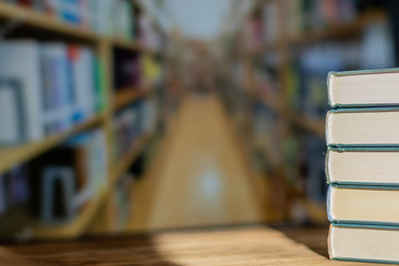 Book stack on the desk in the library room under sunrays