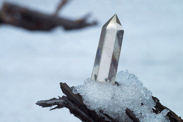 Perfect large shining crystal of transparent quartz in the sunlight on natural snow winter...