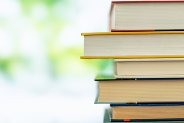 Multikolor book stack in the library room on tabel and blurred trees on street back to school concept