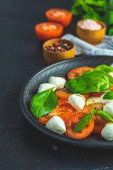 Italian caprese salad in black ceramic plate