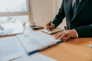 Working process startup. Businessman working at the wood table with new finance project. Modern notebook on table. Pen holding hand
