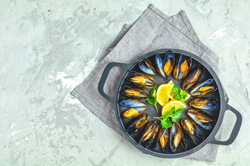 Seafood mussels with lemon and parsley in black metal pan