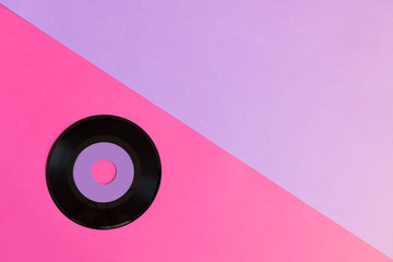 One outdated vinyl disc on a two-ton paper background: pink and violet, pop culture. Top view. Minimalism, top view with copy space