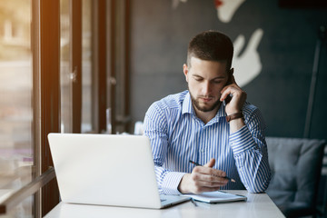 Young man drawing template for the web site associated with digital marketing, current trends and tendencies of UX / UI design. Businessman who rules his company remotely, like a freelancer