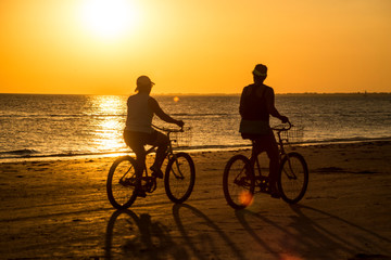 Obraz premium Silhouettes of people on an orange beach at sunset.