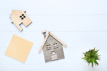 House models with green plant and blank paper on wooden table