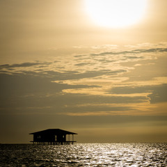 A silhouette of Traditional floating cottage that abandoned by residents of Harapan Island, Indonesia with beautiful orange sky