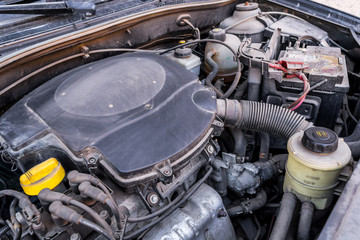 Old used petrol engine with rusty and dirty auto parts, dust accumulation and bad car maintenance. Dusty automobile components. View under the hood. 