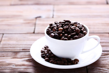 Coffee beans in white cup on brown wooden table