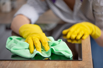 Young woman hands cleaning a modern black induction hob by a rag, housework