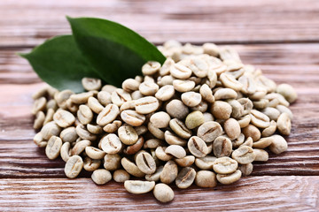 Green coffee beans with green leafs on brown wooden table