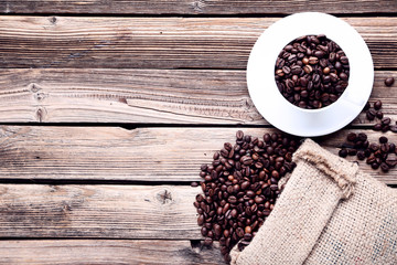 Coffee beans with sackcloth and cup on brown wooden table