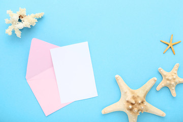 Blank paper with envelope and starfishes on blue background