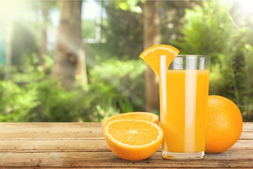 Glass of delicious orange juice on natural background