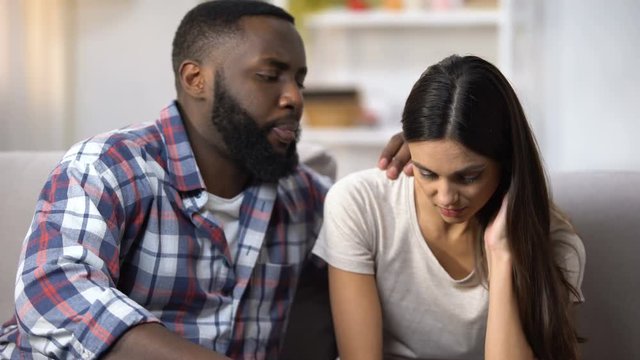 Afro-American man consoling his upset wife, health and life problems, support