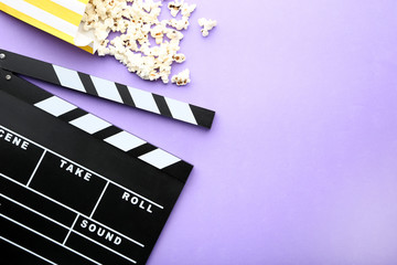 Clapper board with popcorn on purple background