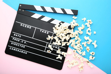 Clapper board with popcorn on colorful background