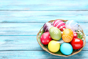 Colorful easter eggs in basket with gypsophila flowers on wooden table