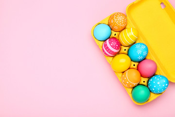 Fototapeta na wymiar Colorful easter eggs in carton box on pink background