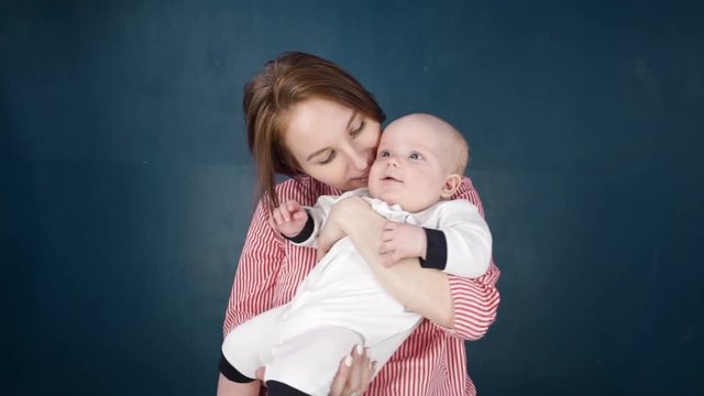 Happy Caucasian people and children. A young mother holds a newborn baby in the air in her arms, kissing him. Mom laughs and smiles at the boy. Fun for a woman, cute boy in her arms. Slow motion. HD