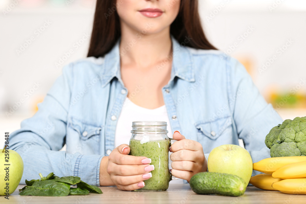 Sticker Beautiful woman drinking fresh smoothie in the kitchen