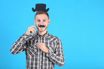 Portrait of young man with paper hat and mustache on blue background
