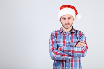 Young man in santa hat on grey background