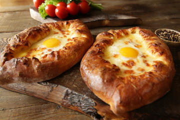 Adjara Khachapuri on wooden boards is baked bread in the shape of a boat with cheese and egg. Traditional Georgian dishes.